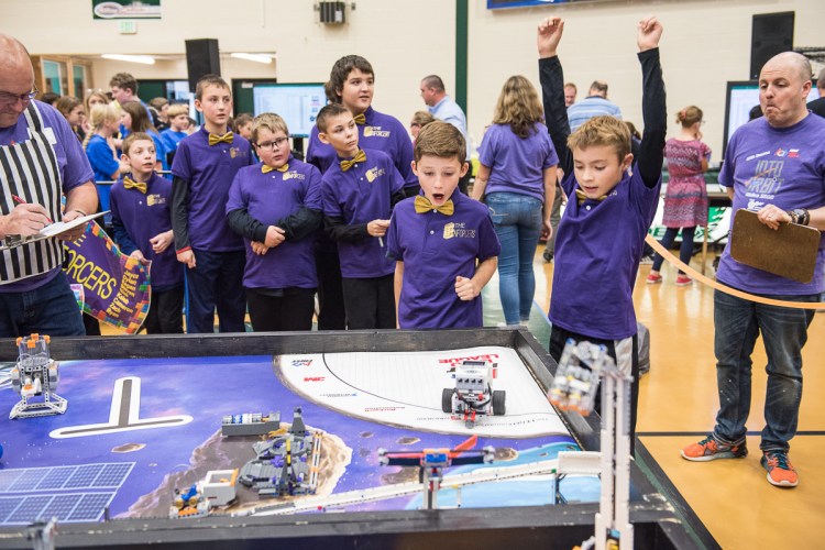 Jayce Thompson raises his hands in victory as his robot completes a task during the Western Maine FIRST Lego League Qualifier at Spruce Mountain High School in Jay on Saturday. Members of his team, The Enforcers, from RSU 16 in Poland react.