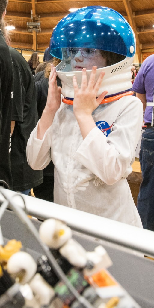 Melissa Finnemore raises the visor of her spacesuit to get a better look at the progress her team's robot was making during Saturday's competition at Spruce Mountain. She is a member of team StarFish from Fairfield.