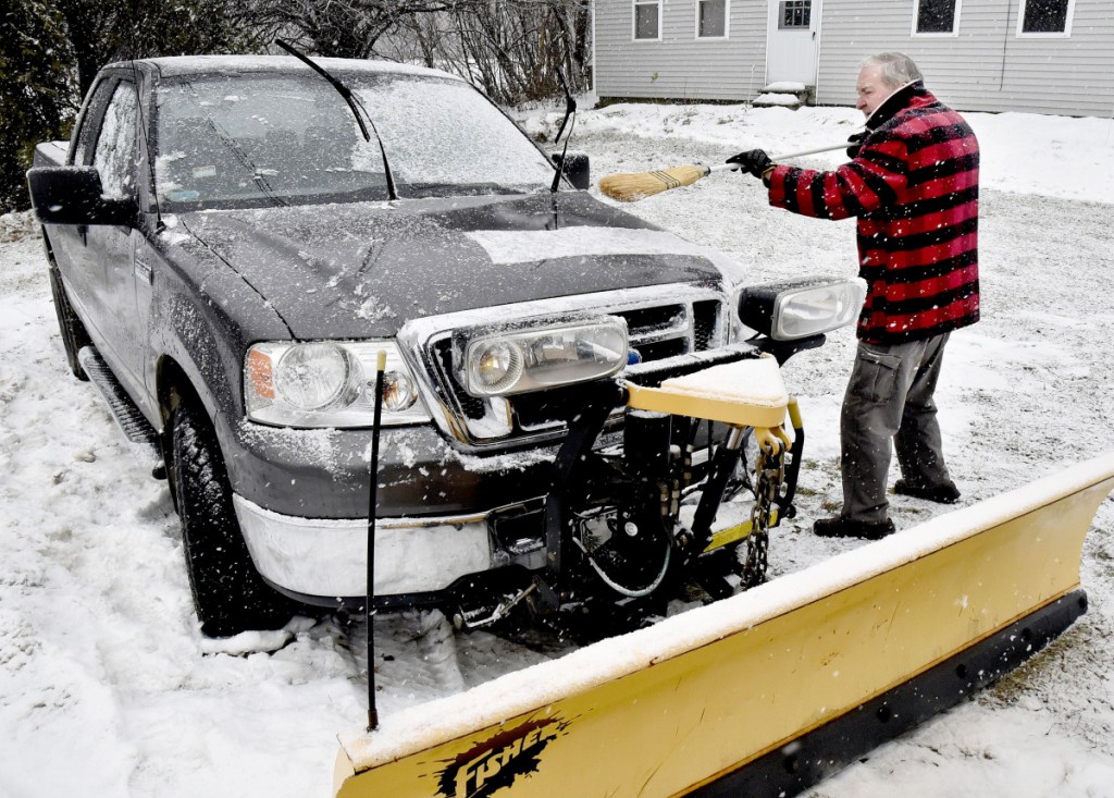 Peter Webb brushes snow off his plow truck as snow falls Tuesday in Skowhegan.
