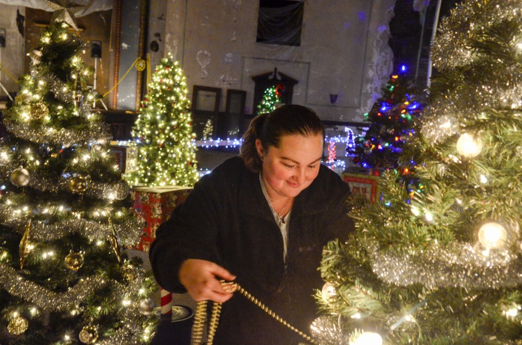 Kayla Guenard decorates the Capital City Coins tree Wednesday at the Colonial Theater in Augusta. The River of Trees event starts Friday and runs through Sunday.