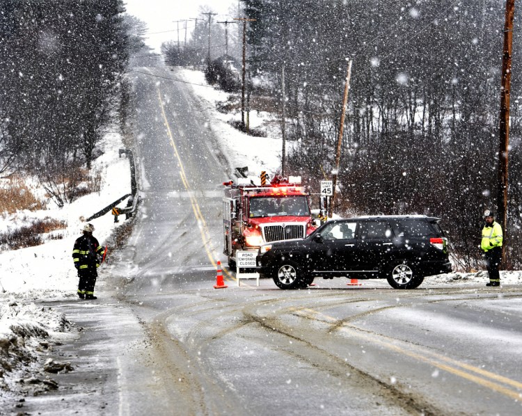 Firefighters from Madison detour traffic at the intersection of Route 43 and Molunkus Road in Cornville as police investigate a fatal accident on Route 43 as snow fell on Sunday.