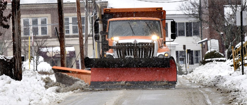 A Waterville Public Works department plow truck clears snow from city streets in Waterville during a snowstorm on Tuesday.
