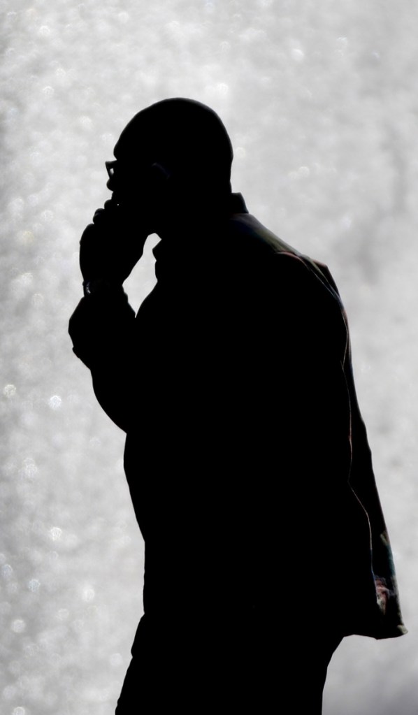 A pedestrian talking on a cellphone is silhouetted in front of a fountain in Philadelphia in 2012.