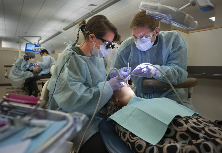 Stephanie Beeckel, left, and Chris Priest give a cleaning to Mary Rena in the Oral Health Center at the University of New England in Portland on Friday. UNE participated in Dentists Who Care for ME, in which dentists provide free care for people who can't afford regular dental care. Beeckel is a third-year dental student and Priest is a first-year dental student at UNE.