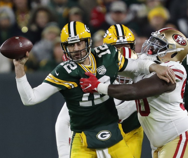Green Bay Packers quarterback Aaron Rodgers (12) throws the ball away as he is tackled by San Francisco 49ers defensive tackle Earl Mitchell (90) during the second half of an NFL football game Monday, Oct. 15, 2018, in Green Bay, Wis. (AP Photo/Matt Ludtke)