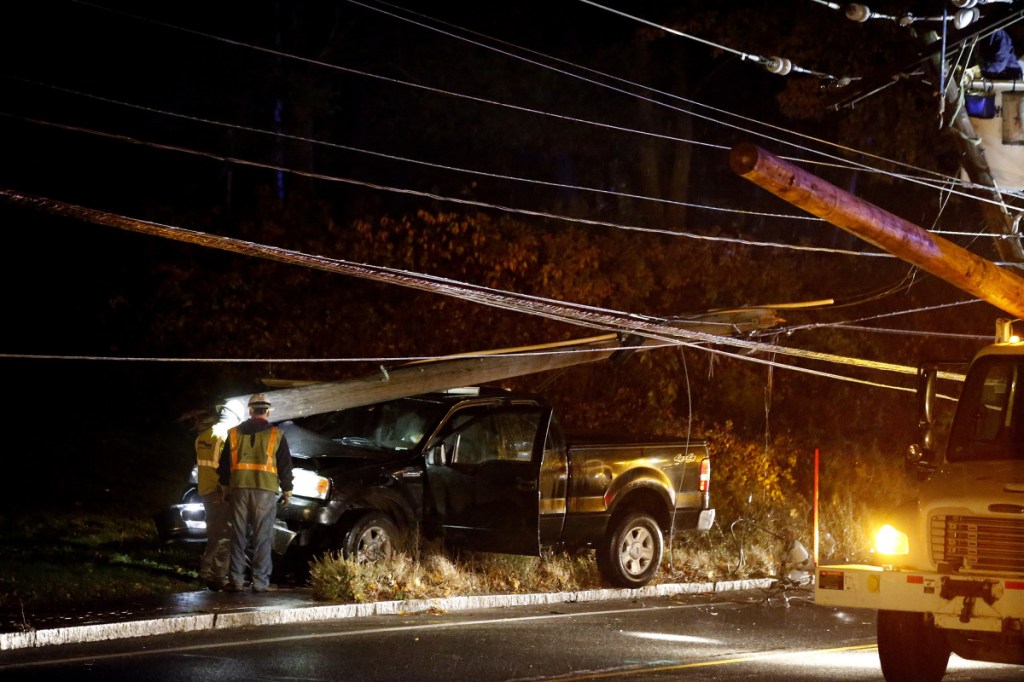 Line workers examine the base of a utility pole and the truck that hit it Tuesday on outer Congress Street. A portion of the road was closed during the repair. Power was out at the Portland International Jetport and nearby areas.