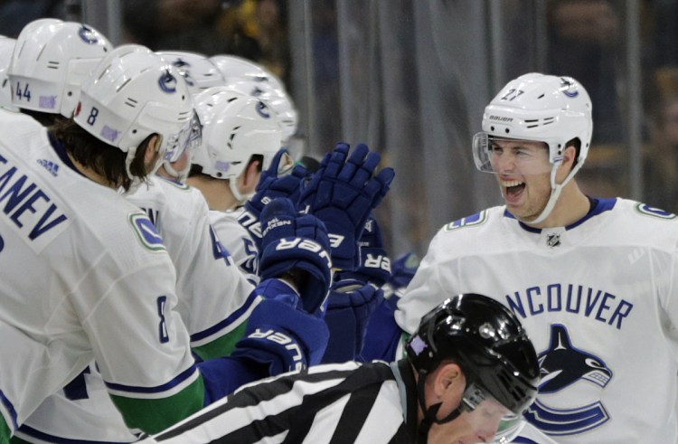 Vancouver players on the bench reach out to defenseman Ben Hutton to celebrate his goal during the second period Thursday night in Boston.