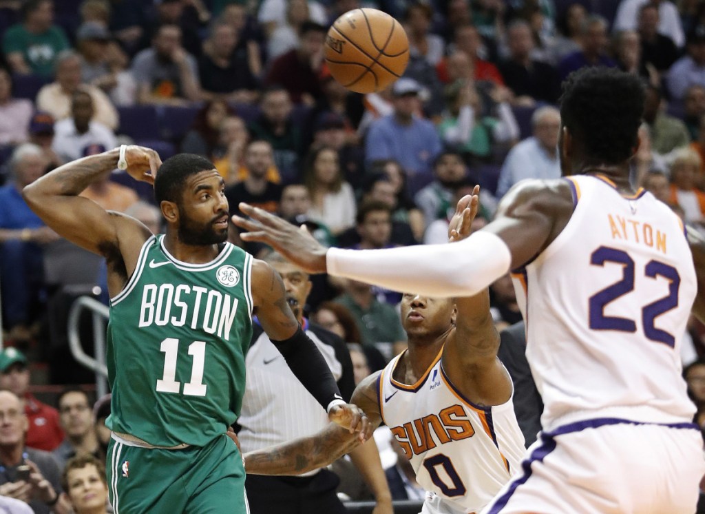 Boston Celtics guard Kyrie Irving (11) throws a pass over Phoenix Suns guard Isaiah Canaan (0) during the first half of an NBA basketball game Thursday, Nov. 8, 2018, in Phoenix.