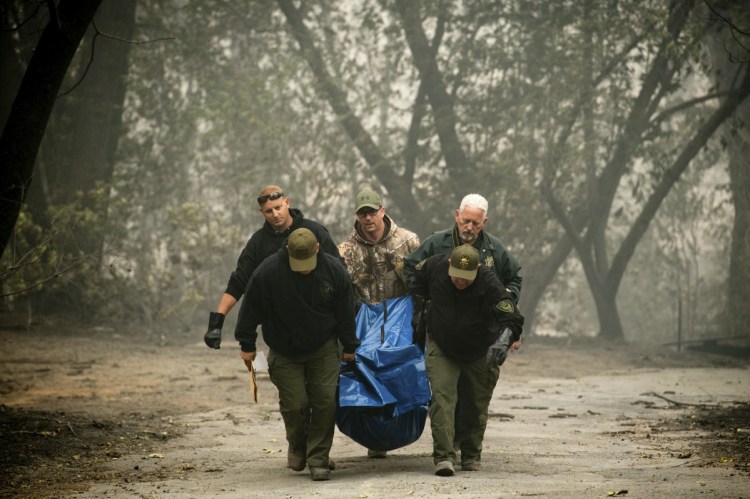 Sheriff's deputies recover the remains of a victim of the Camp Fire on Saturday in Paradise, Calif. 