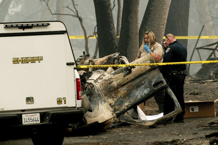 A sheriff's deputy recovers the remains of a Camp Fire victim from an overturned car in Paradise, California, on Thursday.
