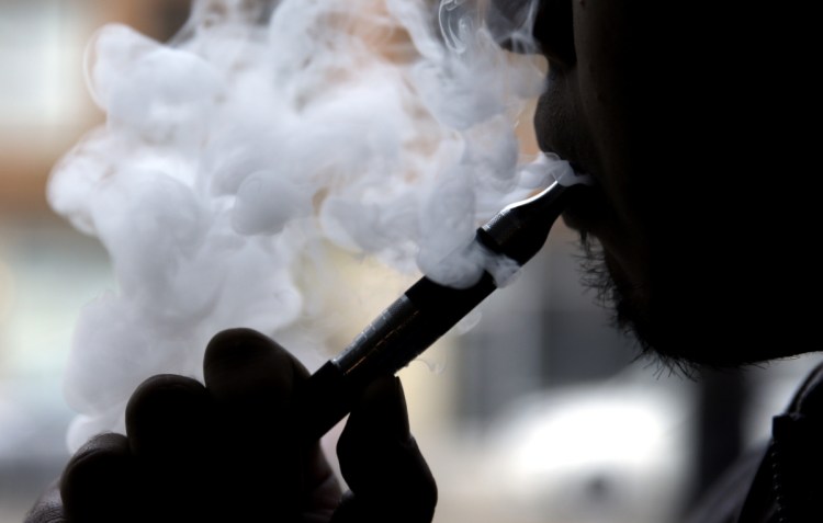 A smoker uses an electronic cigarette. Some makers of the liquid nicotine in electronic cigarettes are using brand names like Thin Mint and Tootsie Roll to sell their wares.