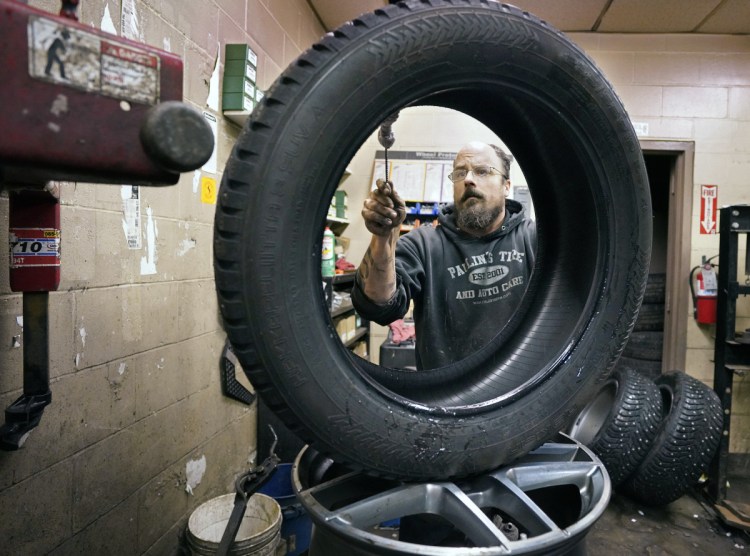Greg Moreau, manager at Paulin's Tire & Auto Care in Portland, cleans off the bead of a studded snow tire that he is changing over for a customer Tuesday. Even with his two-man crew working 12-hour days, Moreau can squeeze in no more than 15 standard tire swaps a day between regular service appointments.
