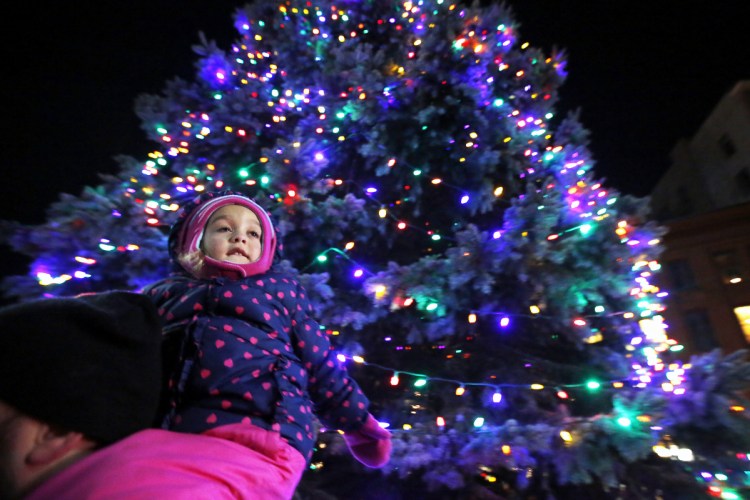 Aleigh Fauth, 3, of South Portland, rides on father Brian Fauth's shoulders just after the tree was lit on Friday in Monument Square in Portland.