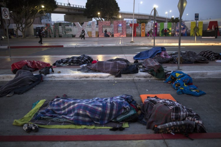 Migrants sleep on a street near the border crossing in Tijuana, Mexico, on Friday.