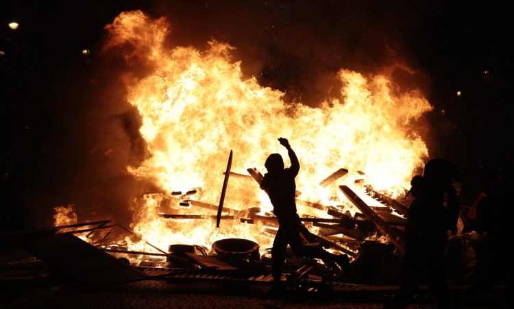 A demonstrator throws debris at a burning barricade Saturday while protesting fuel taxes in Paris.