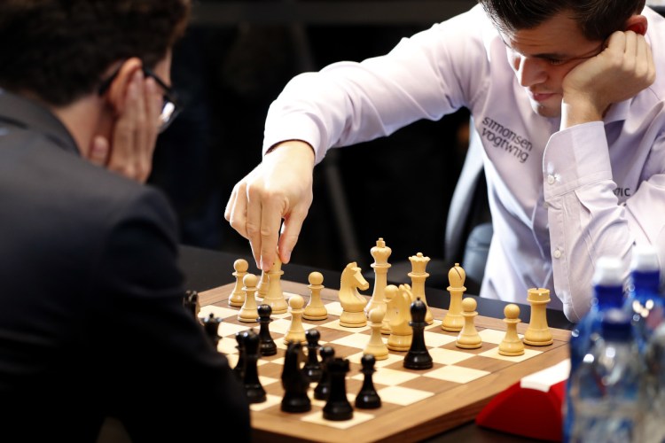 Reigning chess world champion, Norway's Magnus Carlsen, makes a move while playing against American Fabiano Caruana in the final day of the world chess championship in London.