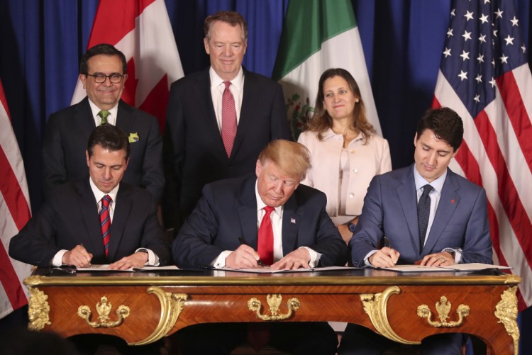 President Trump sits between Canada's Prime Minister Justin Trudeau, right, and Mexico's President Enrique Pena Nieto as they sign the United States-Mexico-Canada Agreement, which that is replacing the NAFTA trade deal, during a ceremony Friday at a hotel before the start of the G20 summit in Buenos Aires, Argentina. The USMCA, as Trump refers to it, still nneds approvald by lawmakers in all three countries.