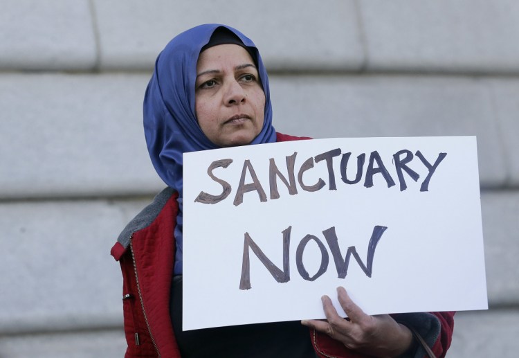 A woman holds a sign at a rally outside of City Hall in San Francisco in 2017. The Trump administration can't withhold over $29 million from six states and New York City in a clash over their immigration policies as "sanctuary" jurisdictions, a federal judge said Friday.