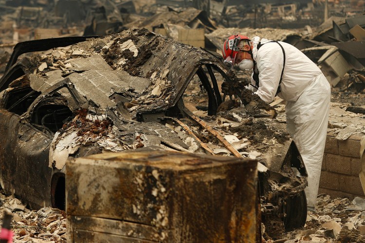 A search-and-rescue worker searches a car for human remains Tuesday at a trailer park in Paradise, Calif., that was burned out by the Camp Fire.