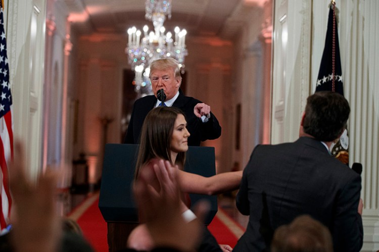 Donald Trump watches as a White House aide reaches to take away a microphone from CNN journalist Jim Acosta during a news conference at the White House in November.