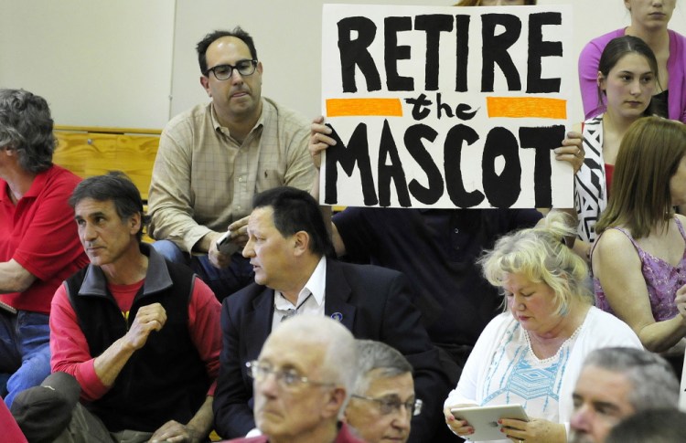 Mark Roman holds a sign protesting use of the name Indian for SAD 54 sports teams during a forum May 4, 2015, in Skowhegan. At far left is former chief of the Penobscot tribe Barry Dana, of Solon.