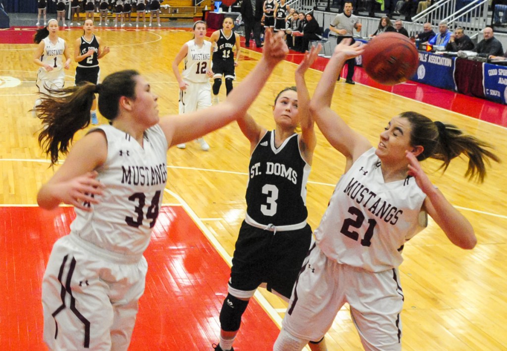 Monmouth center Destiny Clough, left, and guard Abby Ferland, right go for a rebound in front of St. Dom's guard Raleigh Stebbins during a Class C South game last season at the Augusta Civic Center.
