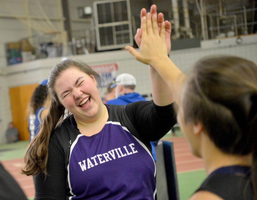 Waterville's Sarah Cox, center, highs-fives teammate Jennasea Hubbard after winning the shot put at the Kennebec Valley Athletic Conference track and field meet championships last Feb. 3 at Bowdoin College in Brunswick.