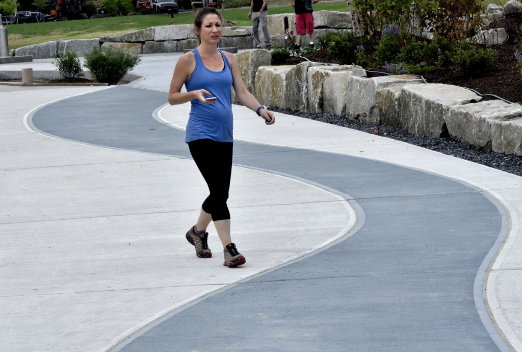 Katie Malone takes a leisurely walk Sept. 17 along the colorful paths at RiverWalk at Head of Falls in Waterville. The city of Waterville is to receive a $7.3 million grant to fund new traffic patterns and other infrastructure improvements downtown.