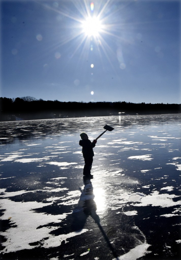 Landon Blaisdell swings an ice auger equal to his own height while he and his family fish on Messalonskee Lake in Oakland on a cold Monday. Landon's father reported the black ice was 4 inches thick.