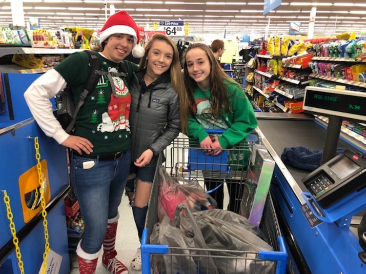 Steph Perkins, left, a Jobs for Maine Graduates specialist, and students Sierah Trask and Susanna Curtis check out after shopping Wednesday for Christmas gifts for needy children.