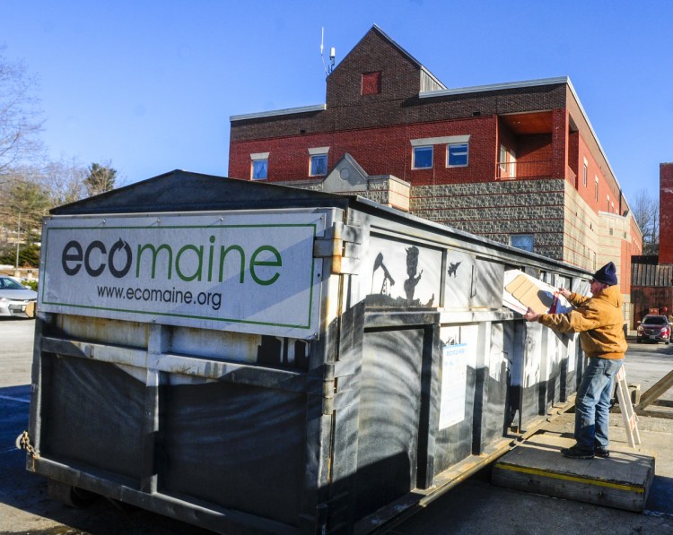 Les Mason puts cardboard into the Ecomaine recycling rolloff container Thursday at the Augusta police station.