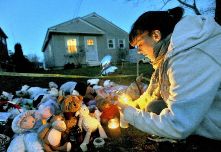 Tara True, of Winslow, lights candles at the ever-growing teddy bear shrine in front of the Violette Avenue residence in Waterville where 20-month-old Ayla Reynolds was last seen in December 2011.