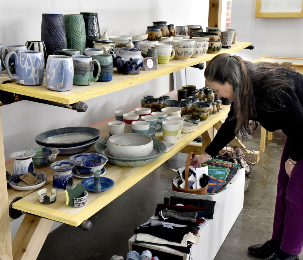 Customer Judy Ayer looks over pottery and knitted items at the holiday bazaar shop at Common Street Arts in the Hathaway Creative Center in Waterville on Thursday.