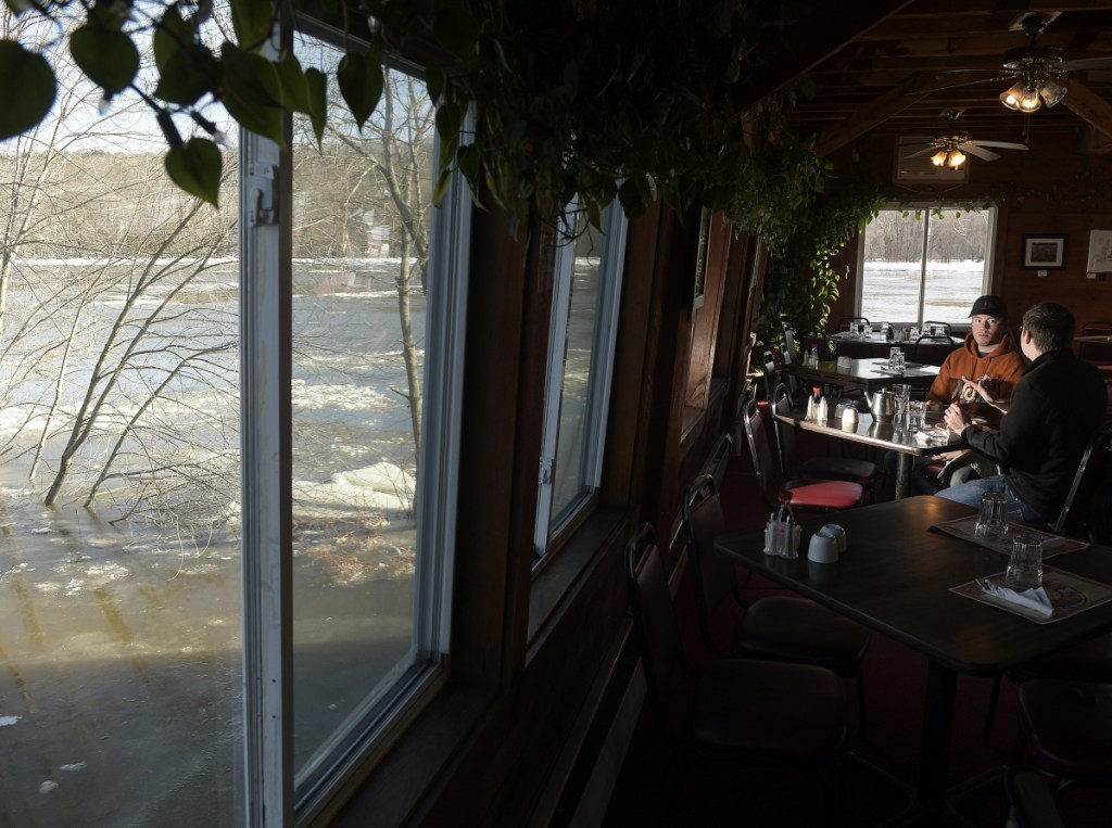 Jake Levesque, left, and Dylan Sirios eat lunch Jan. 14 at the Lucky Garden restaurant as the flooding Kennebec River surrounds them in Hallowell.