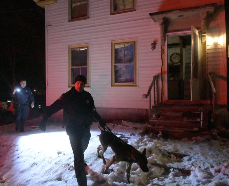 Cpl. Derek Record, left, and Trooper G.J. Neagle, both of the Maine State Police, use dogs to search a home at 39 Patterson St. in Augusta for suspects and drugs.