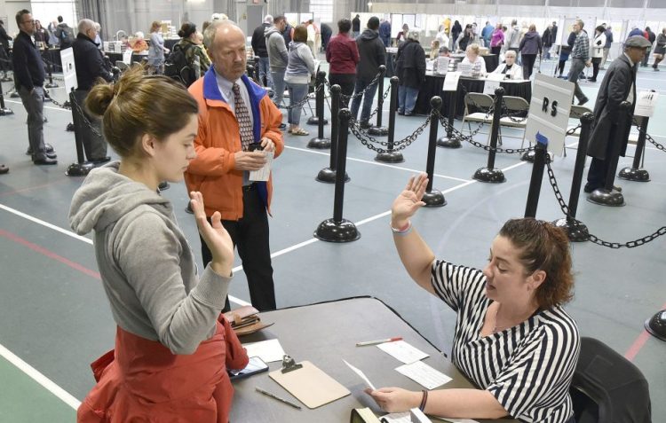Colby College student Alexandria Fraize, left, swears on Nov. 6 the information she gave election clerk Allison Brochu is accurate before voting at Thomas College. City Solicitor Bill Lee observes.