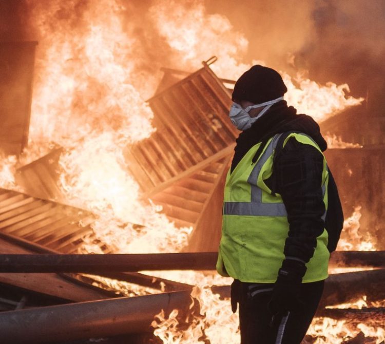 A protester walks past a burning barricade near the Arc de Triomphe during a demonstration Saturday in Paris. It was the third straight weekend of clashes.