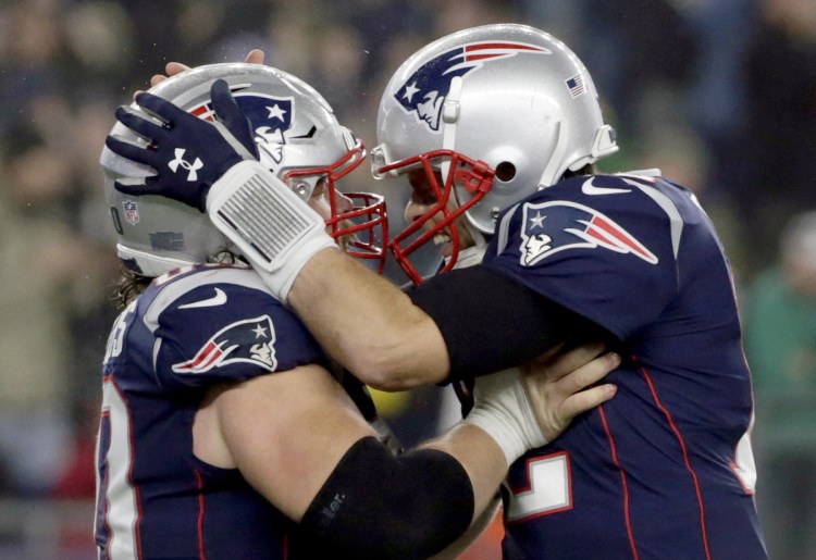 Patriots quarterback Tom Brady, right, celebrates a touchdown run by James Develin, along with center David Andrews, left, during New England's 24-10 win over the Minnesota Vikings on Sunday in Foxborough, Mass.