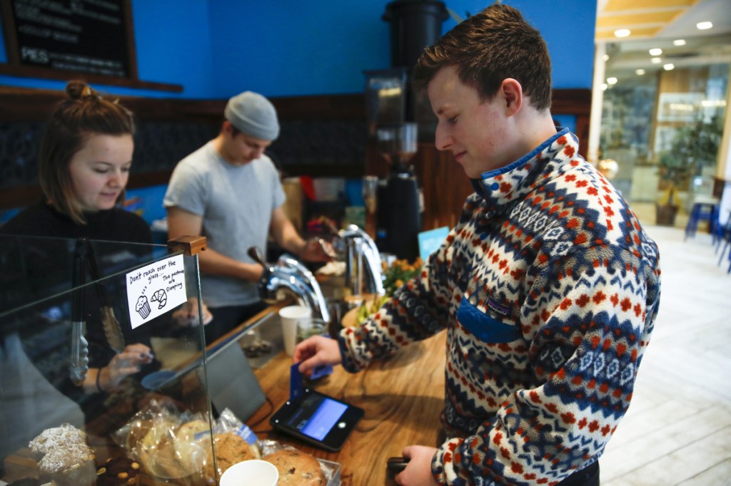 Eli Gitelman swipes his card to pay his bill and add a tip at a Dollop coffee shop in Chicago. More people who pay with a card are encountering a tip screen prompting them to add a gratuity for a service they may not have considered tipping for before, creating a quandary about the tip in the middle of a transaction.
