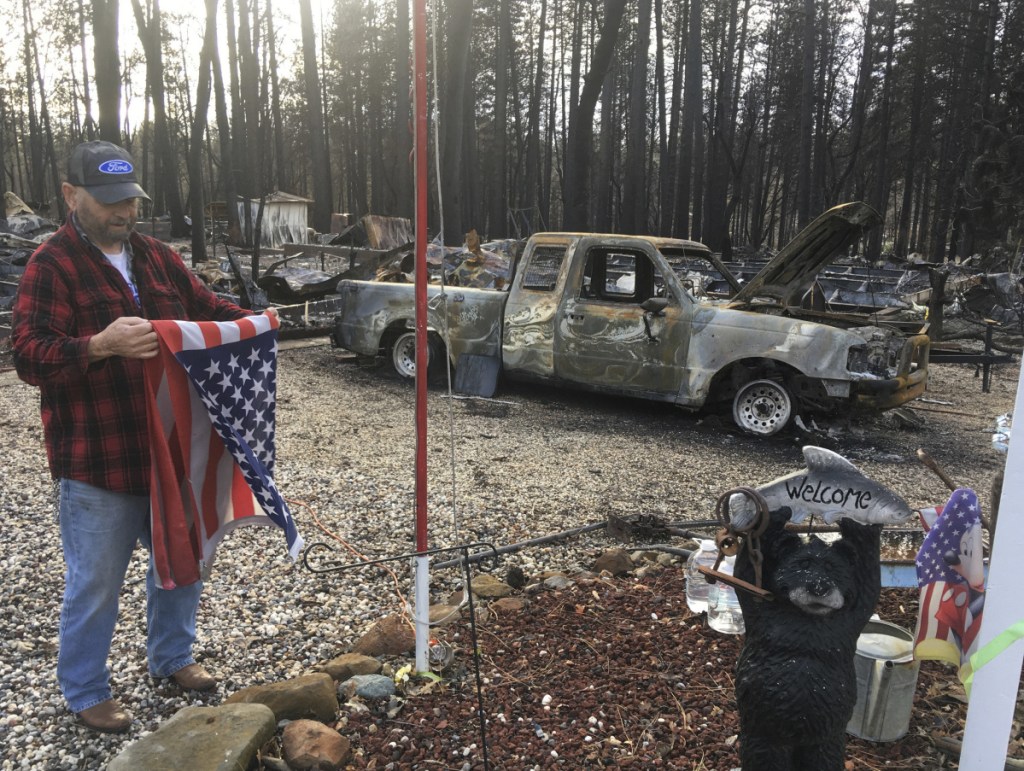 Jerry McLean folds the flag that was flying outside the remains of his home Wednesday, in Paradise, Calif. Some residents of the town devastated by wildfire nearly a month ago were finally allowed to return home.