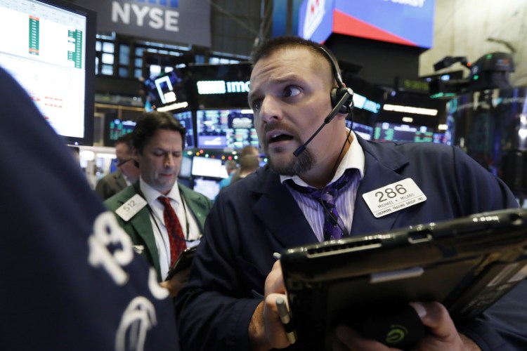Trader Michael Milano, right, works on the floor of the New York Stock Exchange on Monday.