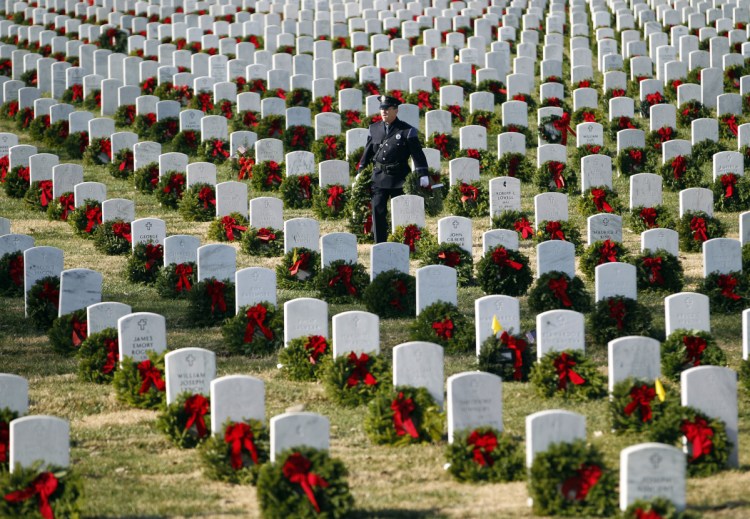 Portland police Officer Terry Fitzgerald places wreaths at Arlington National Cemetery in 2012. Maine's Wreaths Across America has seen its revenues skyrocket from $227,000 in 2011 to $14.6 million last year.