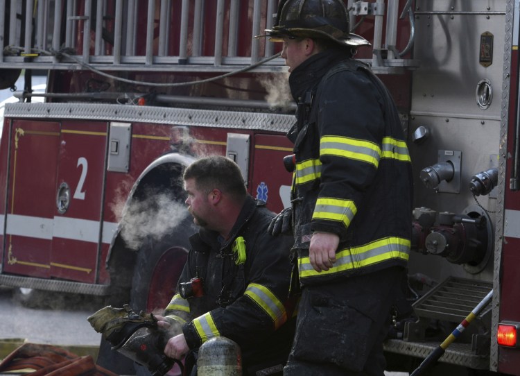 Firefighter Michael Brotherton, left, and a colleague rest for a moment while responding to a fire at an apartment building Sunday in Worcester, Mass. A Massachusetts firefighter injured while battling the early morning blaze has died, officials said.