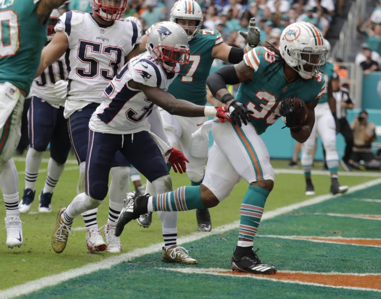 Dolphins running back Brandon Bolden scores one of his two touchdowns Sunday against his former team, helping Miami beat the Patriots, 34-33.