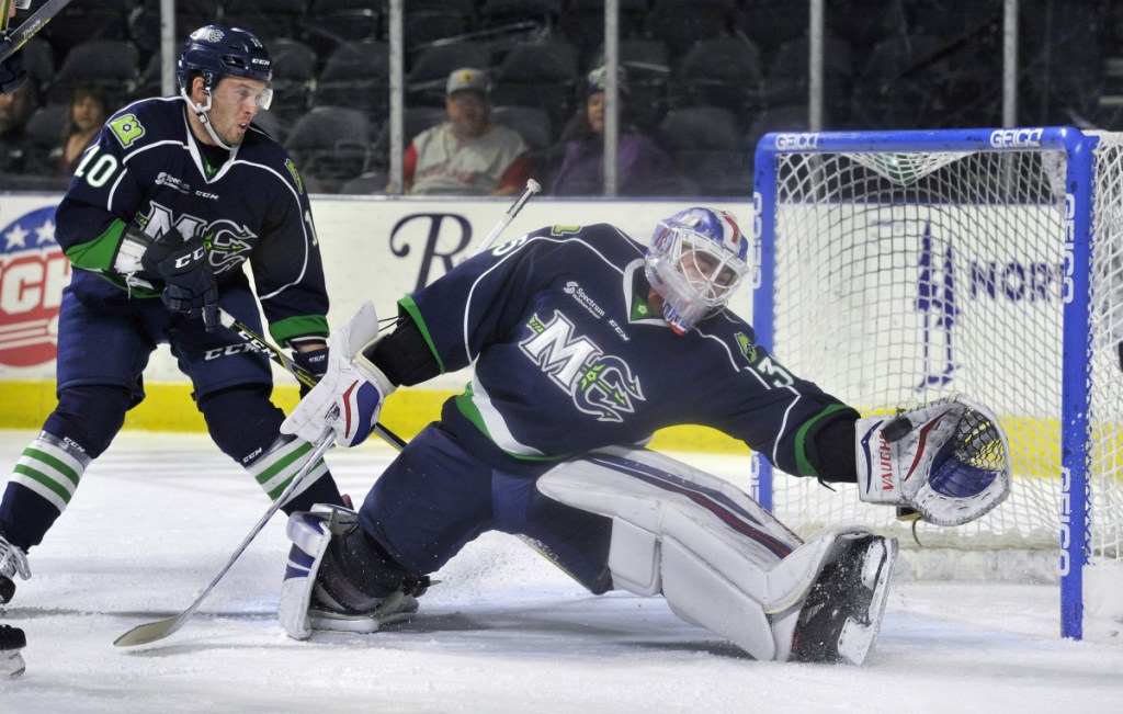 Mariners goalie Brandon Halverson makes a glove save in the first period Sunday as teammate Riley Bourbonnais looks on. Halverson made 40 saves, his second-highest total of the season, helping Maine secure a 4-2 victory at Cross Insurance Arena.