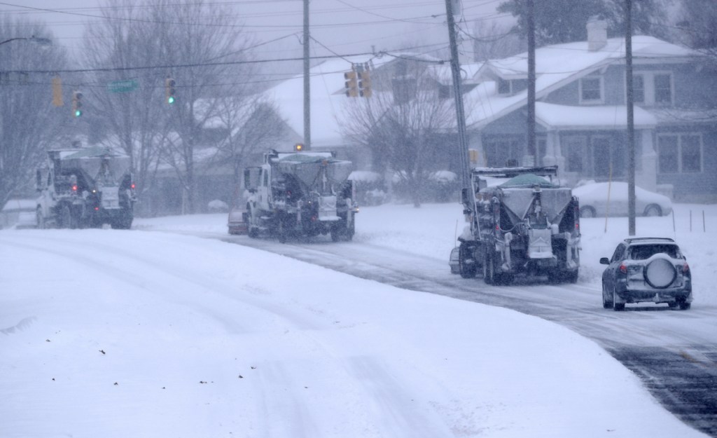 A driver in a small car follows three snow plows down a major road in Greensboro, N.C., on Sunday. A massive storm brought snow, sleet, and freezing rain across a wide swath of the South.