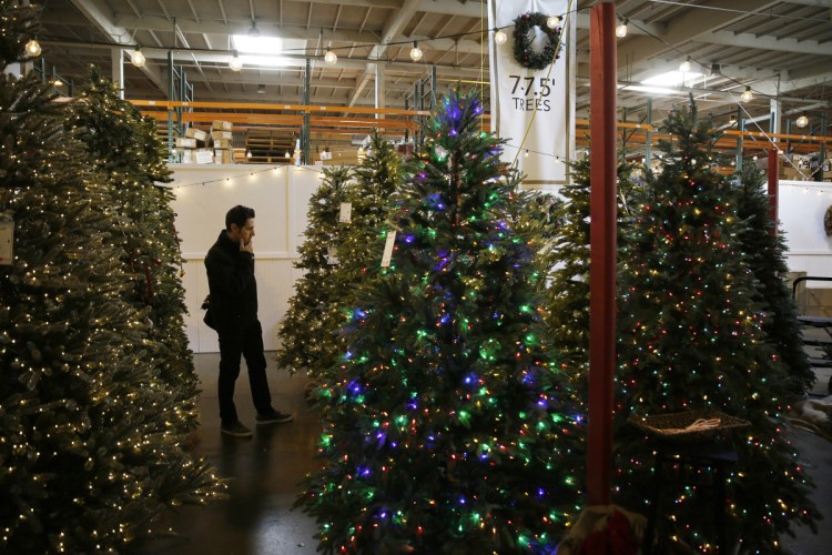 A shopper looks over his options recently at a Burlingame, Calif., outlet store of Balsam Hill, the leading retailer of artificial Christmas trees. About 80 percent of Americans who put up a holiday tree now use a fake one, so tree farmers hope to persuade millennials to go with the real thing as they begin forming traditions with their children.