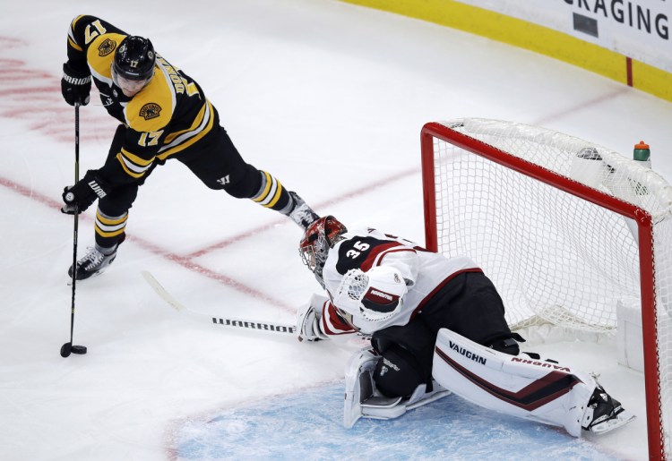 Arizona Coyotes goaltender Darcy Kuemper, right, sweeps his stick as he tries to break up a drive to the net by Boston Bruins center Ryan Donato (17) during the first period of an NHL hockey game in Boston, Tuesday, Dec. 11, 2018. (AP Photo/Charles Krupa)