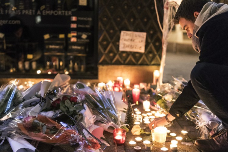 A man lights a candle Wednesday as he pays respects to the victims of an attack the night before that killed two and injured 13 in Strasbourg, eastern France. The suspected gunman had been flagged for extremism and was on a watch list.