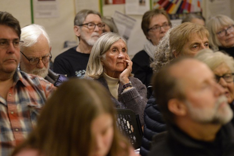 Mere Roberts of Portland, center, listens intently during the Vigil for All Victims of Gun Violence, held Friday evening at the First Parish Church in Portland.